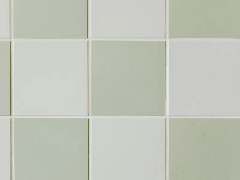 Finished tiling: a wall of sage green and white ceramic tiles with even joints.