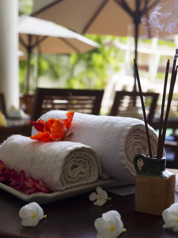 Rolled towels, flowers and incense on a spa table