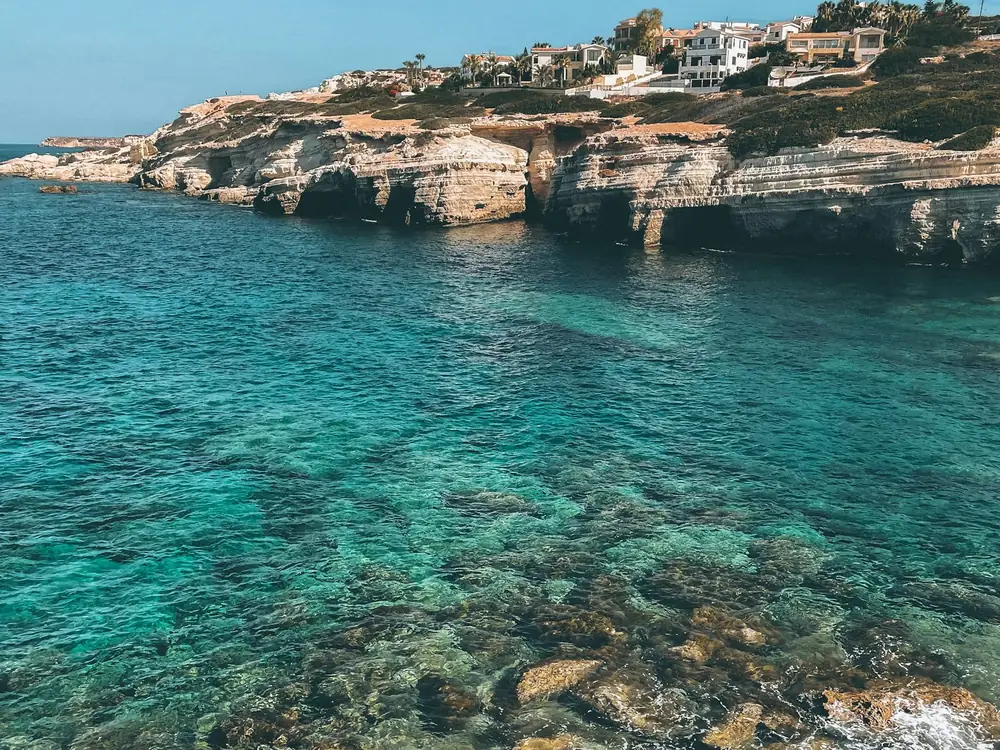Clear turquoise water in a rocky cove below limestone cliffs