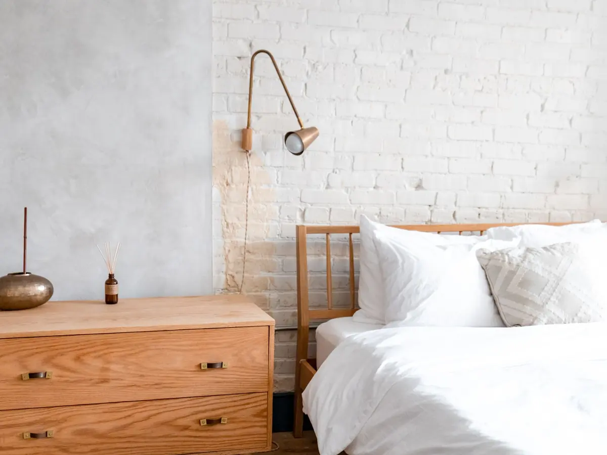 A bedroom with white linen and a wooden bedside table.