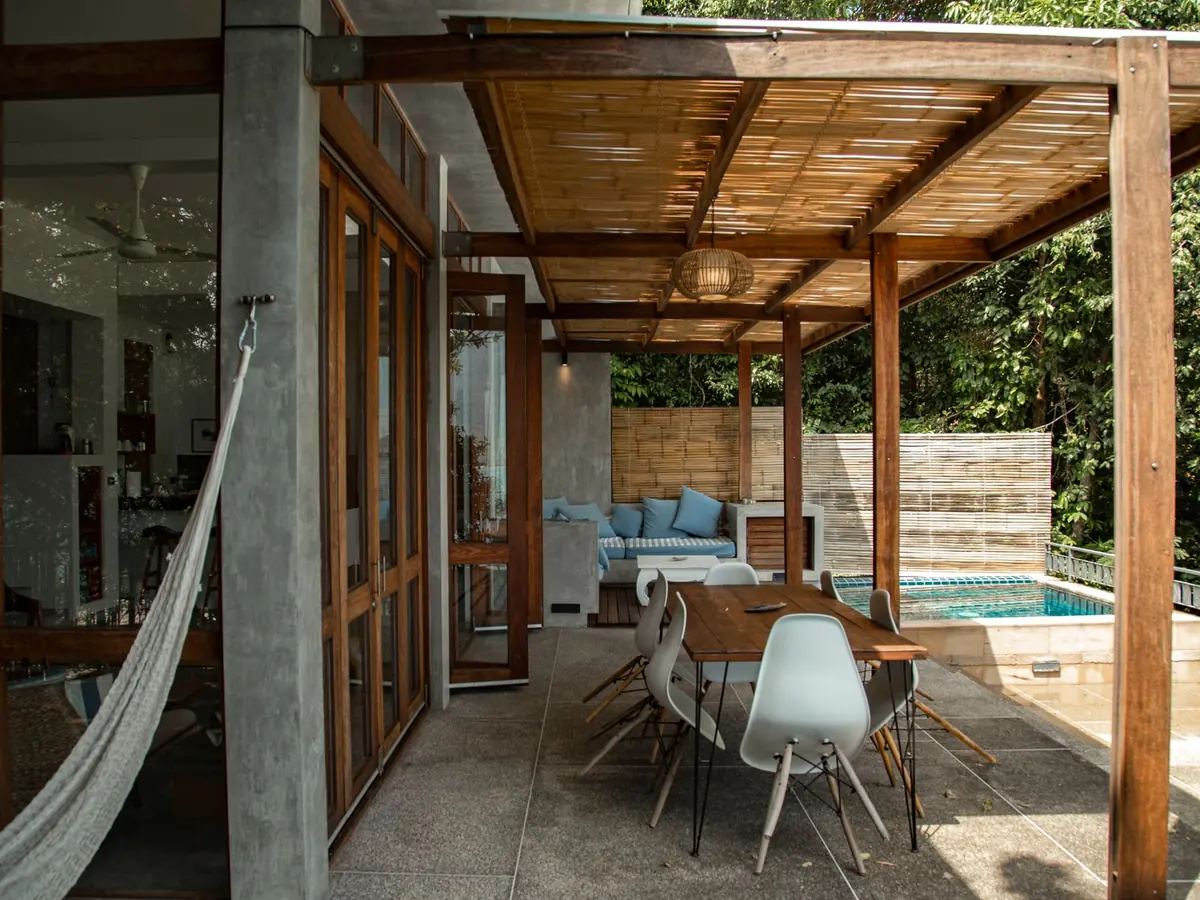 An outdoor dining table under a wooden pergola.